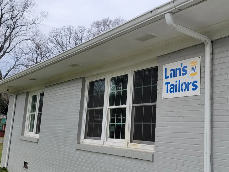 The Lan's Tailors storefront: a grey painted-brick building with a blue Lan's Tailors sign and spool